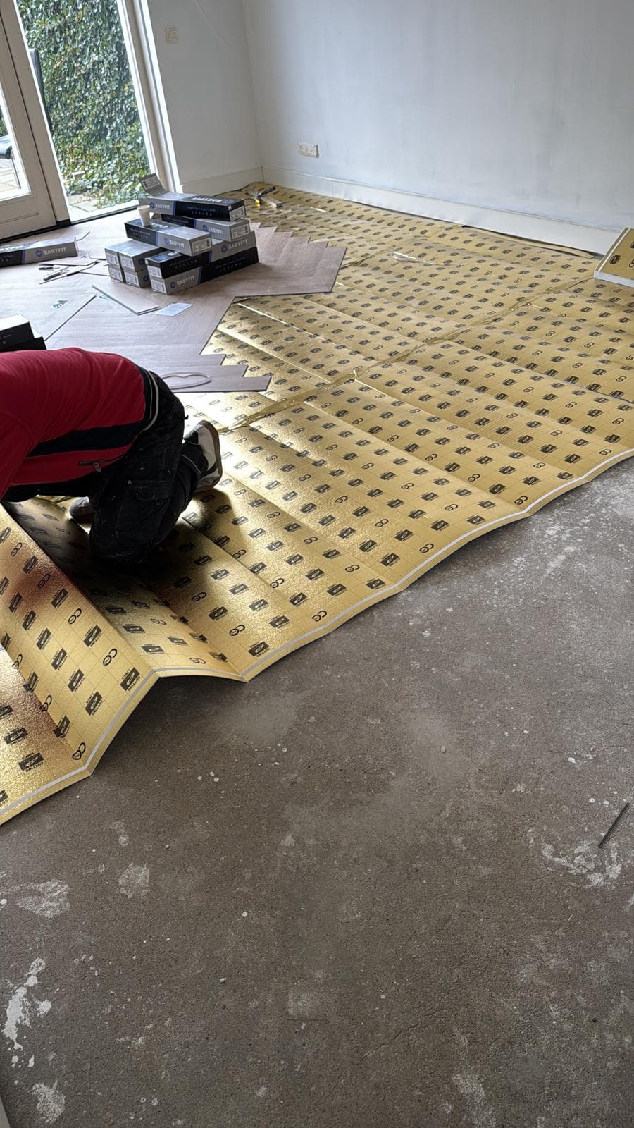 Ondervloer wordt op de betonvloer gelegd als voorbereiding op een nieuwe laminaatvloer